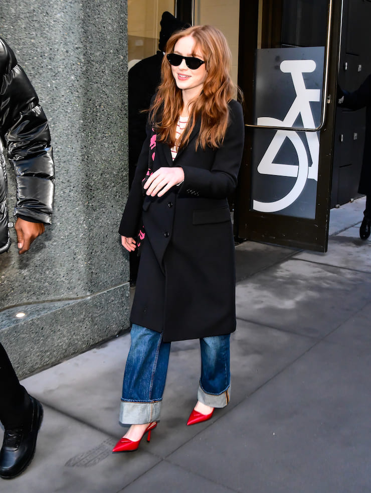 Sadie Sink con cappotto e jeans con maxi risvolti