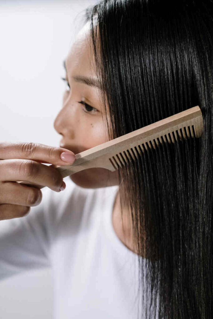 Ragazza asiatica che si pettina i capelli neri lunghi