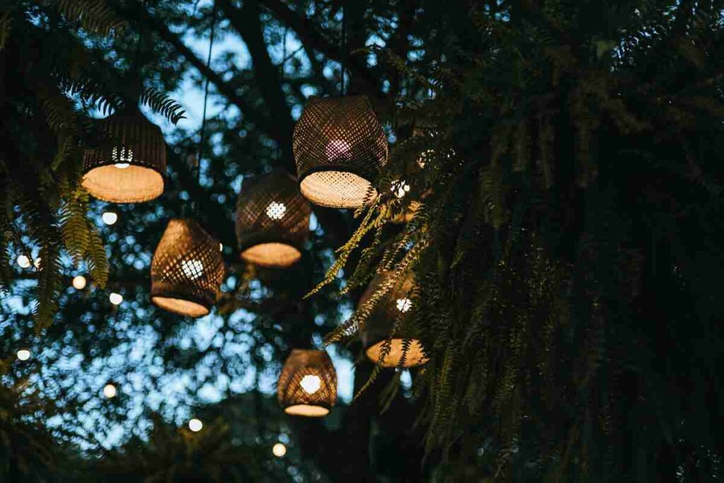 Lanterne illuminate per decorare giardino appese ad alberi di sera