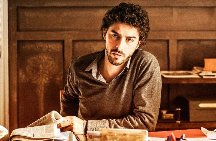 michele riondino seduto alla scrivania in una scena de il giovane montalbano