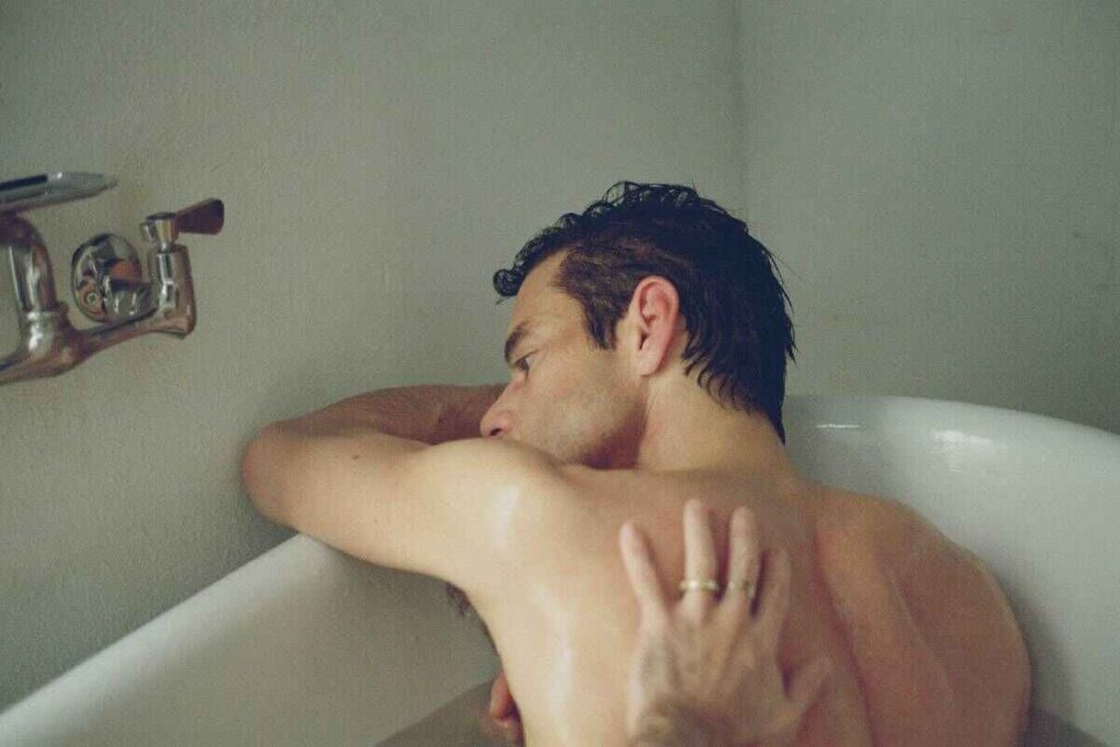 L'attore Rami Malek in una vasca da bagno con una mano maschile appoggiata sulla schiena nel film The man I love