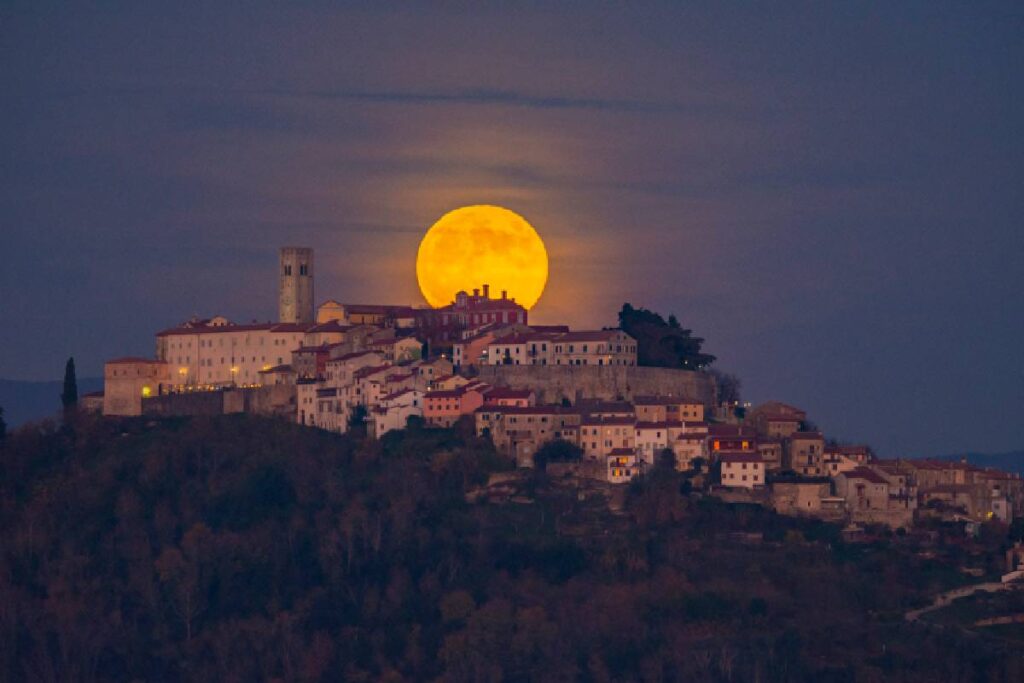 Sole tramonta nascondendosi dietro il borgo di Montona, Istria