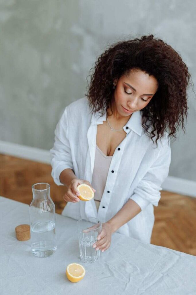 donna spreme limone in bicchiere d'acqua