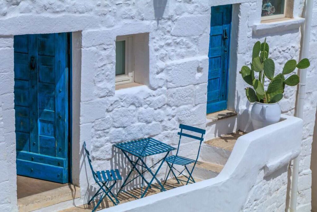 Casa stile balneare con pareti bianche e tavolino con sedie azzurro