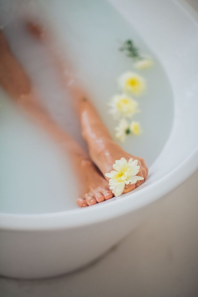 piedi in vasca da bagno con acqua e fiori gialli