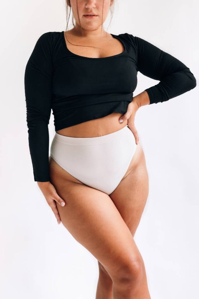 donna in posa con slip bianchi e maglia nera a maniche lunghe