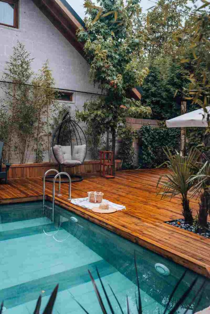 Piscina con piante e dondolo sullo sfondo