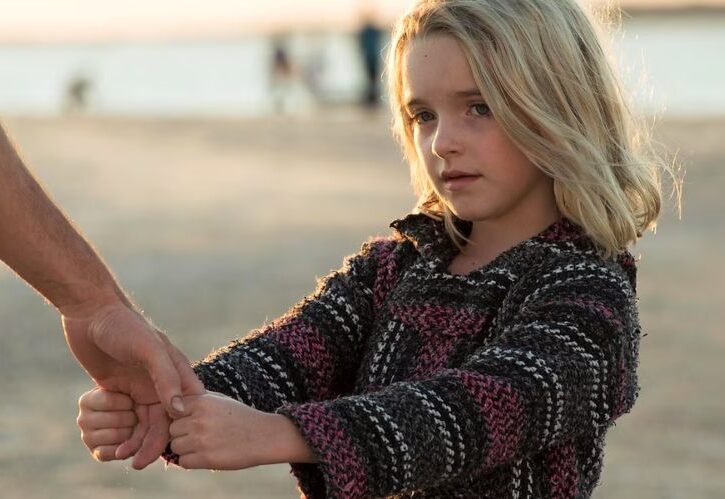 una bambina bionda tiene la mano di un adulto