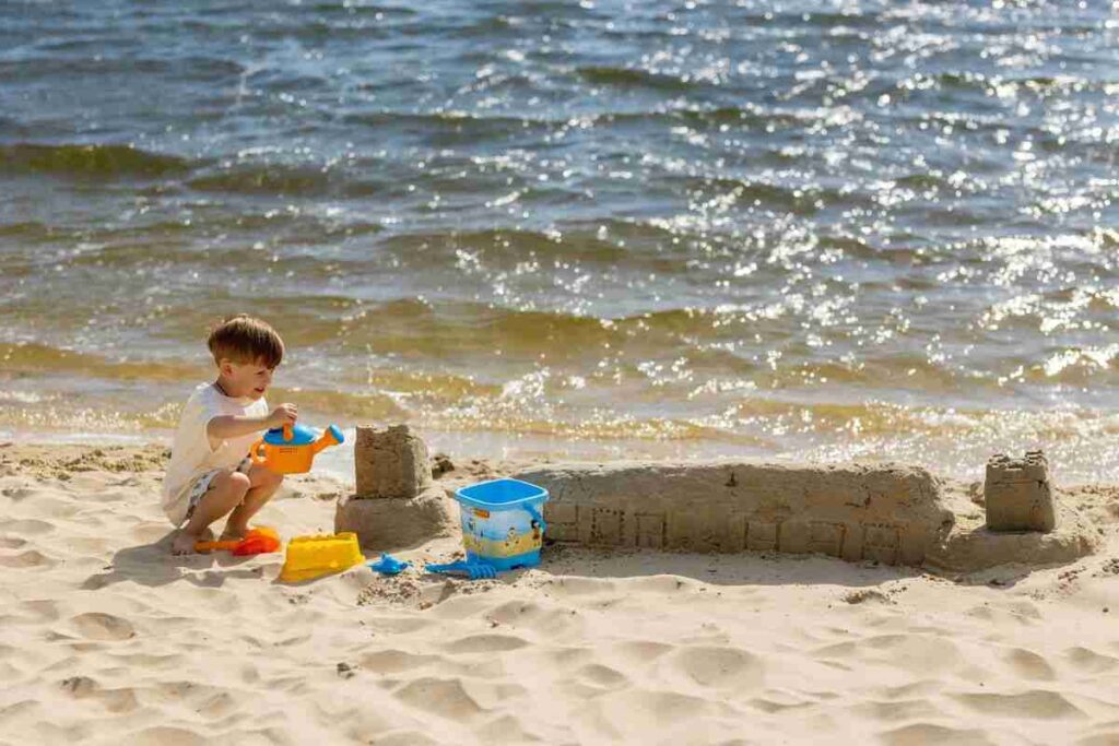 bambino che fa castello di sabbia vicino al mare