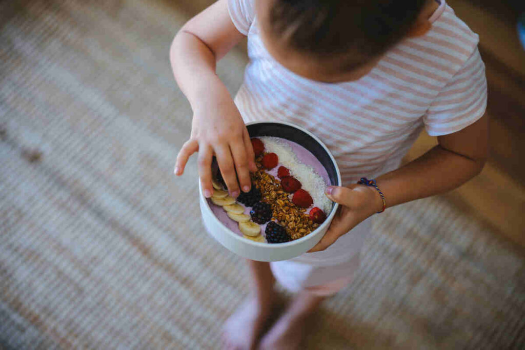 bambina dall'alto con in un mano uno smoothie con con frutta