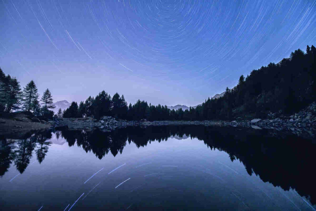 Star trail in the night sky over Lago Azzurro, Madesimo, Valle Spluga, Valtellina, Sondrio province, Lombardy, Italy