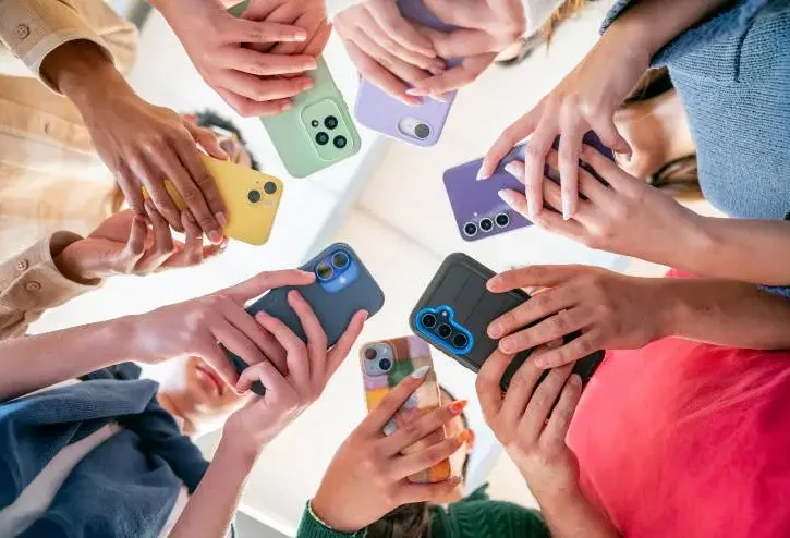 Gruppo di amici in cerchio che tengono i loro telefoni