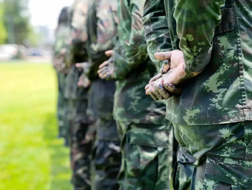 Soldati in uniforme militare mimetica in posizione di riposo, in piedi.