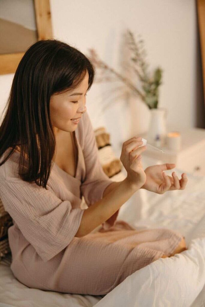 donna sul letto che applica olio su polso