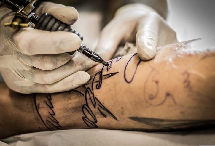 tatuatore fa un tatuaggio su un avambraccio