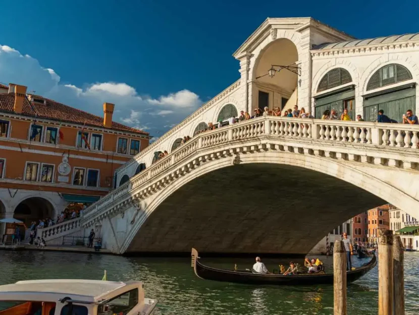 persone sopra il ponte di Rialto e una gondola che passa sotto