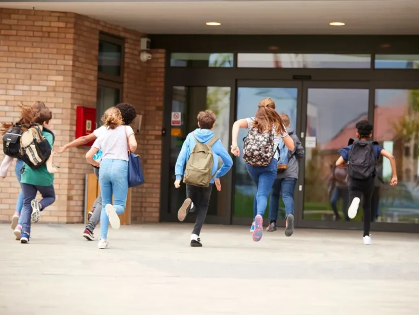 Adolescenti che corrono verso l'ingresso della scuola