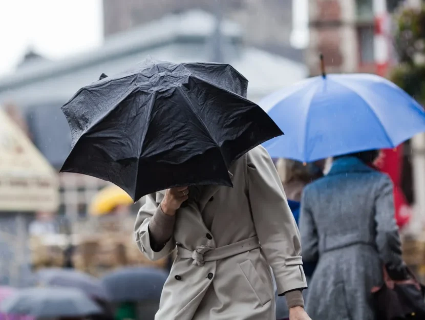 persone si riparano dalla pioggia e dal vento con l'ombrello