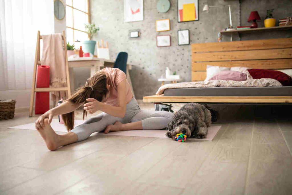 donna che fa yoga a casa insieme al cane