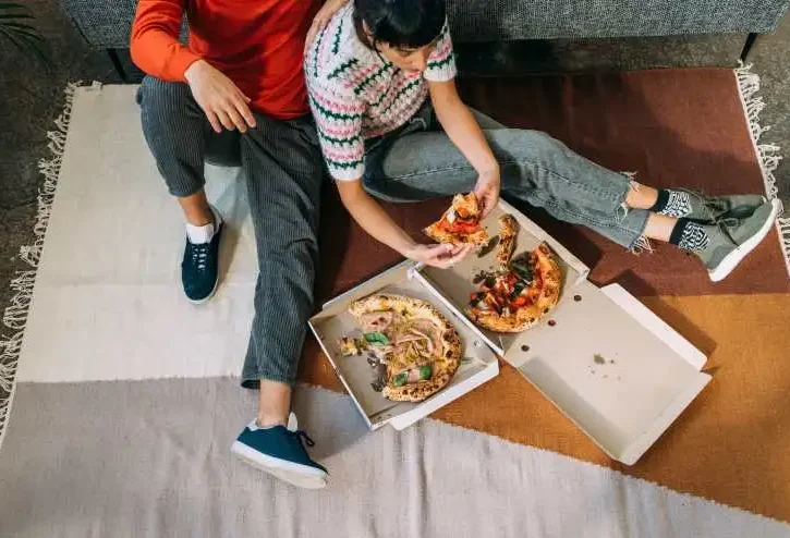 coppia mangia la pizza dai cartoni