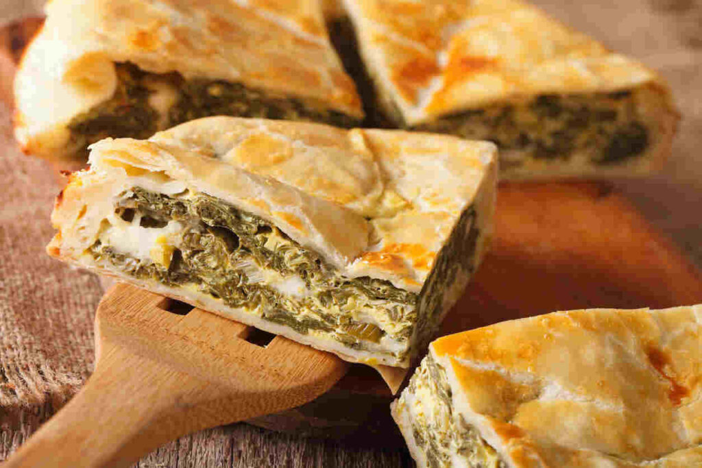 fette di torta salata con scarola su tagliere di legno