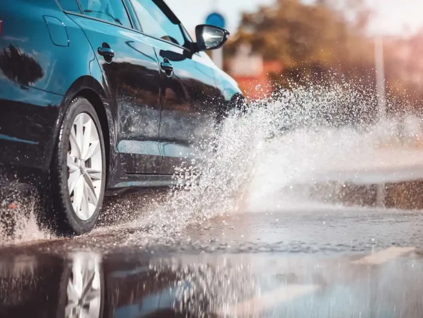 Auto che viaggia attraverso la pozzanghera e schizzi d'acqua