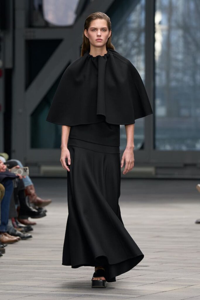 Modella con abito cappa in passerella da Calvin Klein