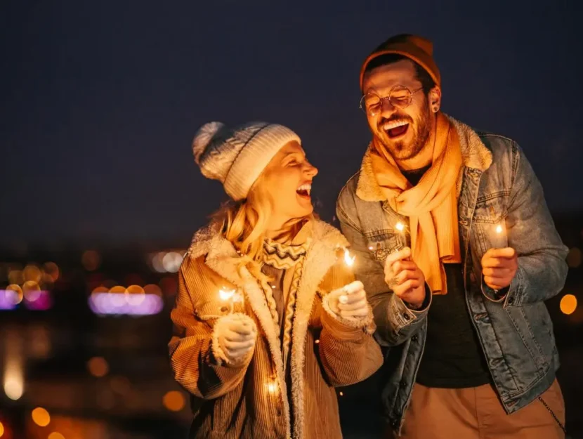 Coppia che festeggia il nuovo anno con stelle filanti all'aperto