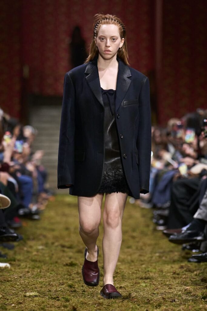 Modella con look total black e messy alla sfilata di Miu Miu