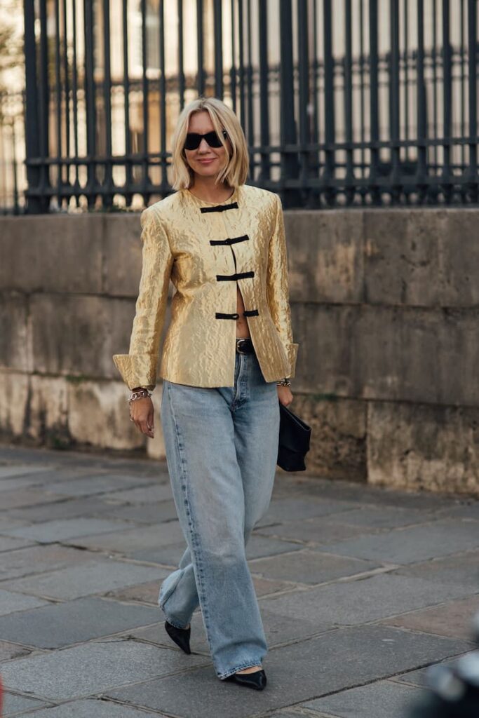 Ragazza con giacchina oro, jeans larghi e scarpe con il tacco