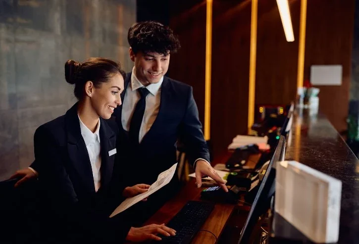 Receptionist felici che collaborano mentre lavorano su un computer alla reception dell'hotel