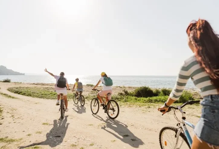 un gruppo di quattro ragazzi che va in bicicletta lungo un sentiero sterrato vicino al mare