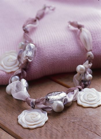 <p><b>COLLANA DI ORGANZA</b></p><p>Per realizzare questa deliziosa collana <b>ti serviranno</b>: 3 ciondoli a fiore di madreperla, 4 perle grandi di vetro color argento, 8 perle bianche di vetro di colore di grandezza diversa, cm 50 di nastro di organza bianco alto cm 4, cm 50 di nastro di organza grigio chiaro alto cm 4, cm 50 di nastro di raso argento alto cm 1, 3 anellini, 1 chiusura a gancio per tessuto, pinze a becco sottile. Naturalmente puoi variare le <b>tonalità di colore</b> in modo da ottenere l'effetto che preferisci.</p><p>Unisci i tre nastri tra loro con un nodo al centro e fissa a questo un fiore di madreperla da agganciare tramite un anellino di metallo. Infila, da entrambe le estremità, una perla grande di vetro argentato e due perline bianche, poi attorciglia i nastri in modo da creare un altro <b>nodo</b>. Utilizzando altri due anellini in metallo fissa ai nodi appena creati gli altri due fiori in madreperla e inserisci nuovamente una perla grande attraverso le estremità della collana, oltre a due piccole perle bianche. Annoda e taglia l'organza seguendo la <b>lunghezza</b> che desideri. Inserisci alle estremità la <b>chiusura</b> per stoffa, ripiegando, con le pinze, le due alette.</p><p>Vuoi un'<b>idea alternativa</b>? Scopri la <b>collana di riciclo</b> alla <b>pagina seguente</b>.</p>