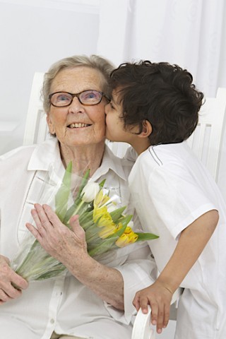 19 Mar 2014 --- Boy offering flowers to his grandmother. --- Image by © CHASSENET / BSIP/BSIP/Corbis