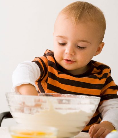 <p>Non è mai troppo presto per iniziare a <b>cucinare</b> con <b>mamma</b> e papà: già verso i <b>18 mesi</b> (ma anche prima) i <b>bambini</b> adorano sporcarsi le mani con la <b>farina</b>, manipolare i legumi secchi o la <b>pasta</b> cruda. Certo, non è un vero e proprio "cucinare" ma li mette già in contatto con i cibi e li fa toccare con mano consistenze e profumi!</p><p>A questa età puoi proporre il <b>gioco del travaso</b>: disponi davanti al bambino tante ciotole e riempile (non tutte) con cibi secchi più diversi. Il bambino sarà curiosissimo di scoprire che sensazione sente mettendo le mani nella farina o nel riso e perderà molto tempo cercando di travasarli da una ciotola all'altra. Non aver paura di sporcare casa! Proteggi i vestiti del bimbo e fallo "lavorare" in una zona circoscritta che ti sarà più facile pulire.</p><p><i>Attenzione alla sicurezza</i>: <b>non lasciare mai solo il bambino</b> a giocare con pasta e riso! Potrebbe portarli alla bocca e soffocarsi.</p>