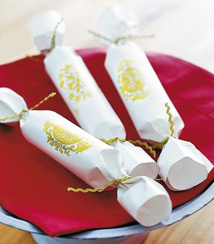 <p> <b>Pacchetti caramella</b><br />Sulla carta da pacco bianca, disegna con l’oro un motivo a stencil. Avvolgi il regalo in modo da formare un cilindro e chiudi le due estremità annodando una fettuccia a zig-zag, sempre dorata. Appoggia il tutto su una tovaglietta rossa.</p>