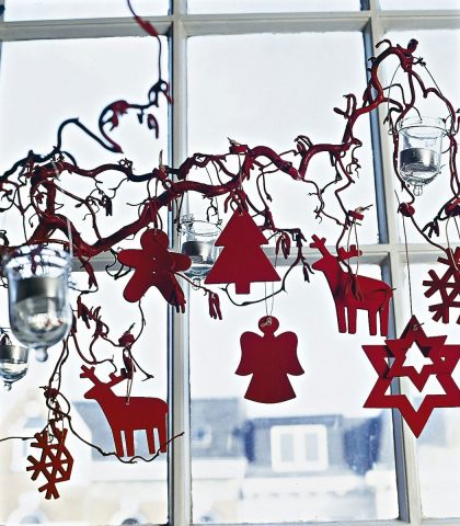 <p><b>Al posto dell’abete</b><br>Un ramo di salice ricciolo arreda lo spazio davanti alla finestra. Figure stilizzate di angeli, renne e stelle, ritagliate nel panno rosso, completano la composizione, insieme ai lumini accesi nei vasetti di vetro.</p>