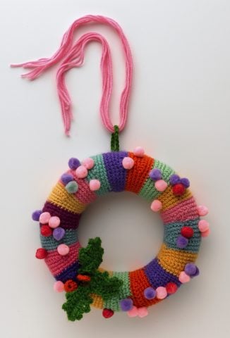 <p><b>GHIRLANDE DI STOFFA</b></p><p> </p><p>Occorrente: ghirlanda di polistirolo con diametro esterno cm 20, pom pon colorati, avanzi di lana, uncinetto n. 4, forbici, cutter, agoda lana, filo di ferro sottile, spilli. Con il <b>cutter</b> taglia a metà la ghirlanda in modo da avere due semicerchi. Avvia una catenella di 30 m e chiudi a cerchio. Lavora a m. bassa in <b>tondo</b> alternando i colori a piacere. Per dare rotondità, ogni 6 giri lav. nel seguente modo: 1 m. bss., 12 m. bs., 1 m. bss.; gira il lavoro e fai 1 m. bss. sulla m. bss. del giro precedente., 12 m. bs., 1 m. bss.; gira il lavoro e prosegui in tondo a m. bs. Arrivata a una <b>lunghezza</b> sufficiente per rivestire la corona, chiudi il lav. e taglia il filo. Inserisci nel tubolare le due metà e chiudi con ago e filo.</p>