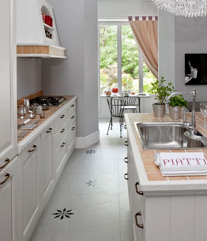 <p> <b>SOLUZIONI PER LA CUCINA</b><br />Il <b>piano lavoro piastrellato</b> è facile da pulire, si mantiene a lungo nel tempo e decora con vivacità. I <b>pensili in legno</b> modanato dalle sfumature color panna, bianco e tortora danno luce alla stanza. Aggiungi tanti vasetti di metallo o una cassetta in vimini con le <b>erbe aromatiche</b>, durante le cene potrai utilizzarle come centrotavola. Il pavimento è vecchio? Se puoi attuare modifiche, vernicia le piastrelle oppure decora con gli <a href="https://www.donnamoderna.com/casa/fai-da-te/stencil-decorazioni-fai-da-te-casa" target="_self"><b>stencil</b></a>. Scegli le mascherine nei negozi di bricolage o disegna tu un motivo da riprodurre, il pavimento avrà una seconda vita.</p>