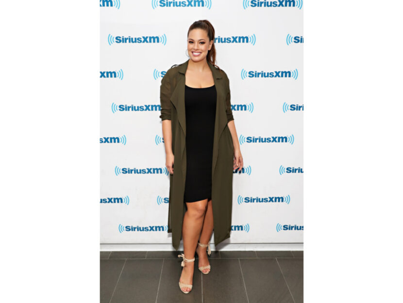 <p style="text-align: left;" data-mce-style="text-align: left;">Ashley Graham indossa un abito a tubino scuro sotto a uno spolverino che camuffa l'eventuale addome prominente</p>